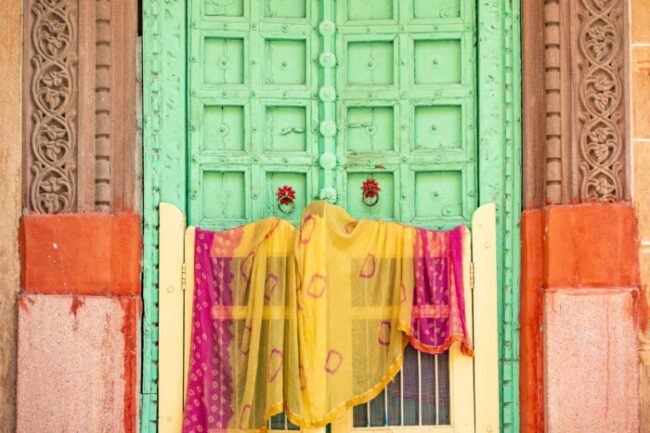 vista impressionante de uma home indiana tradicional com uma porta de madeira verde e a roupa indiana tradicional colorida